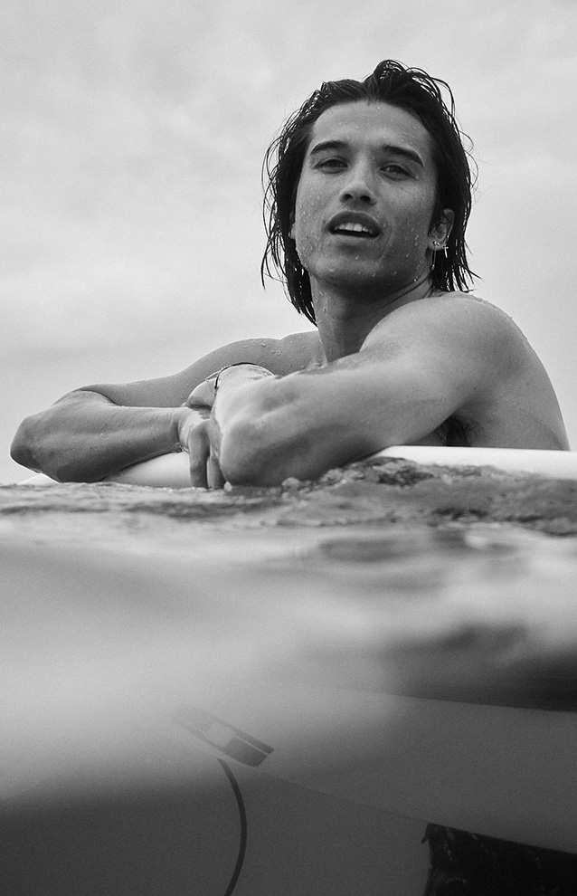 closeup of a man floating in the ocean holding onto his surfboard