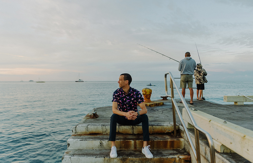 a person sitting on a dock with a couple of men fishing