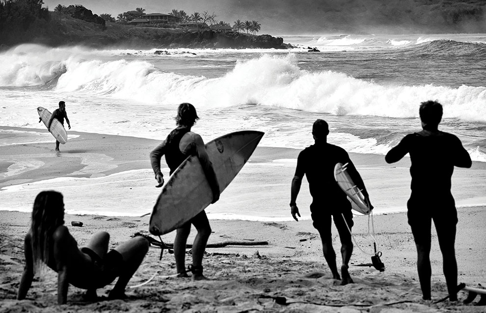 a group of surfers walking on the beach