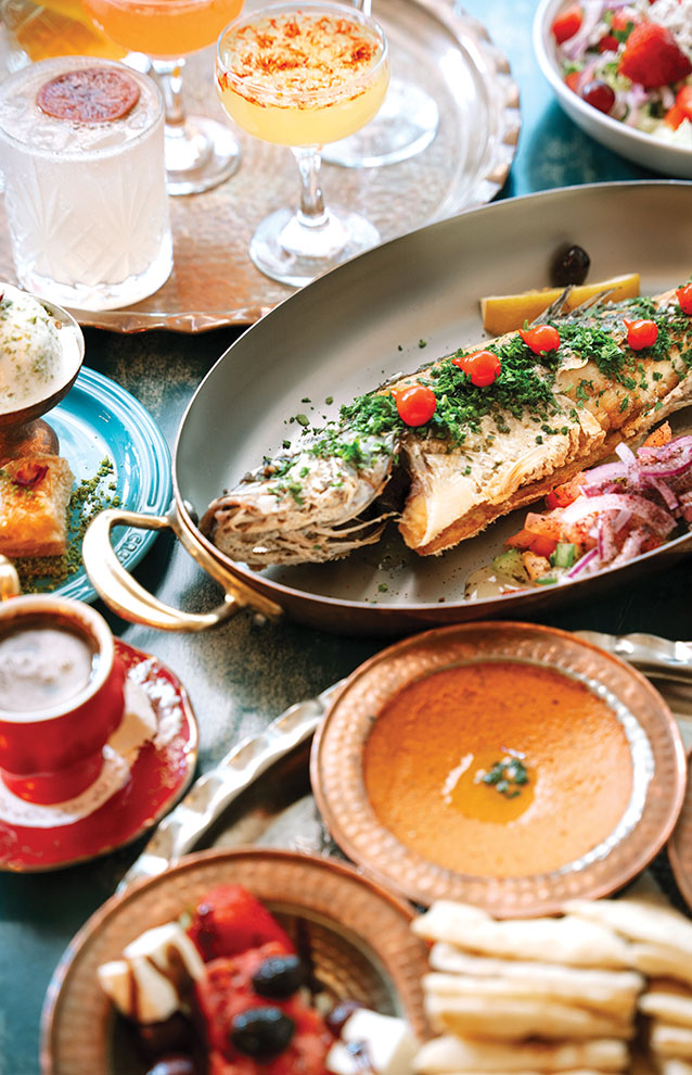 a large fish with vegetables and sauces on a table