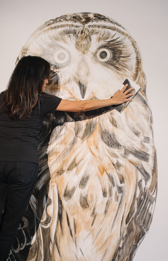 a person in all black clothing erasing art from a wall
