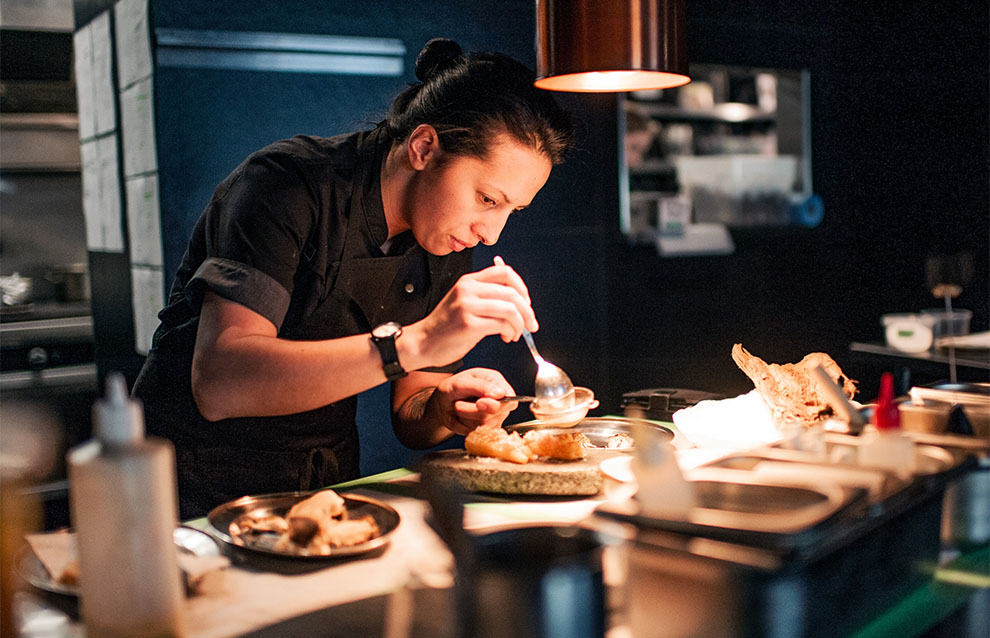 a chef plating a dish in a dimly lit kitchen