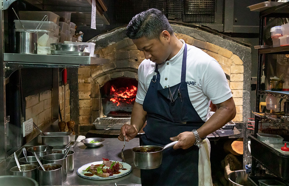 a chef in the kitchen plating a dish 