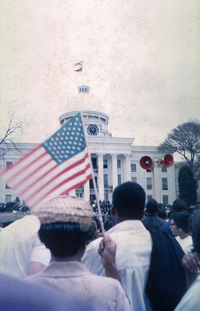 an old photograph of people in front of a white building waving an American flag