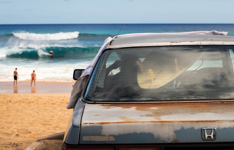 the back of a car overlooking the beach view with two people on the shore