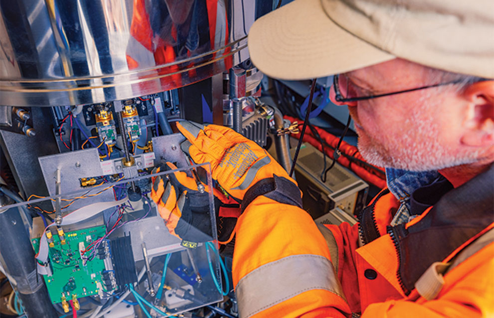 a person tending to a weather machine, wires and panels