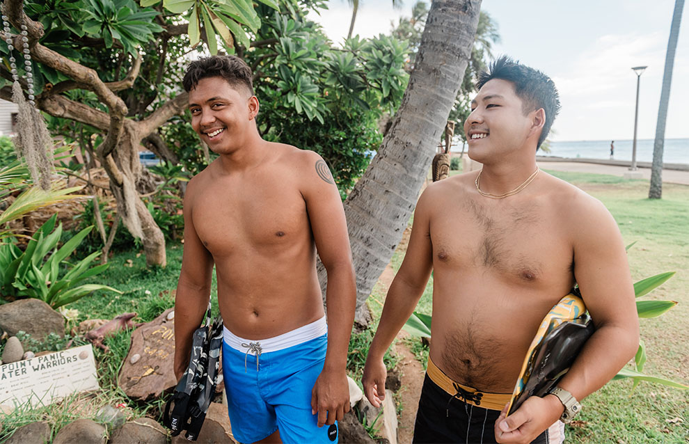 two shirtless people with surfboards