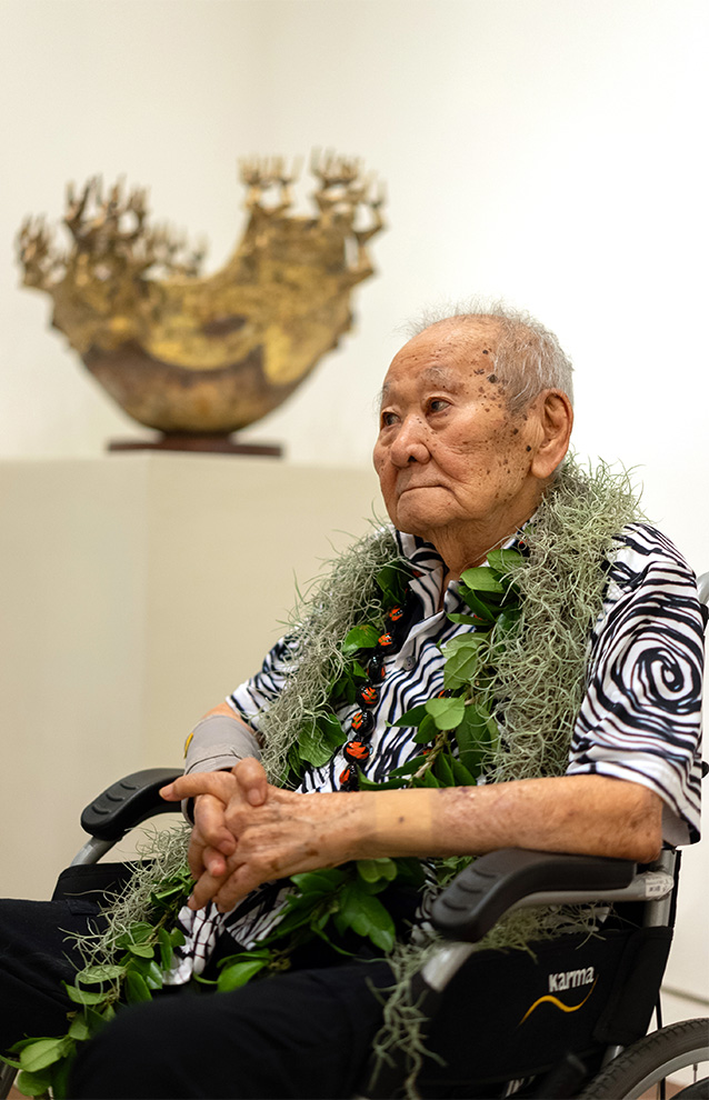 side portrait of a person sitting beside a sculpture