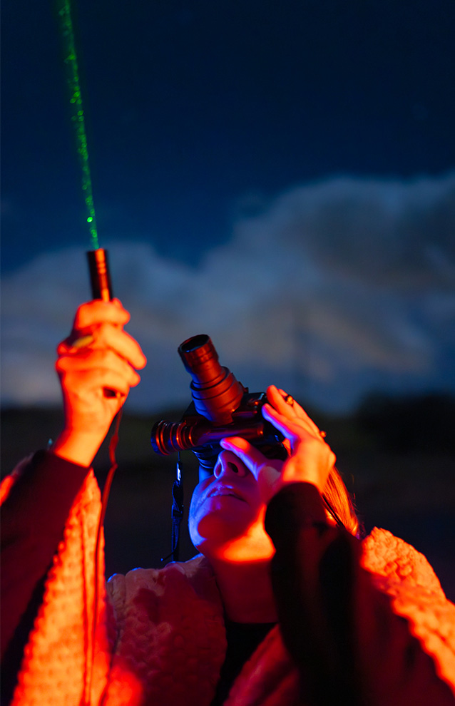 a person looking up at the sky with binoculars, at night
