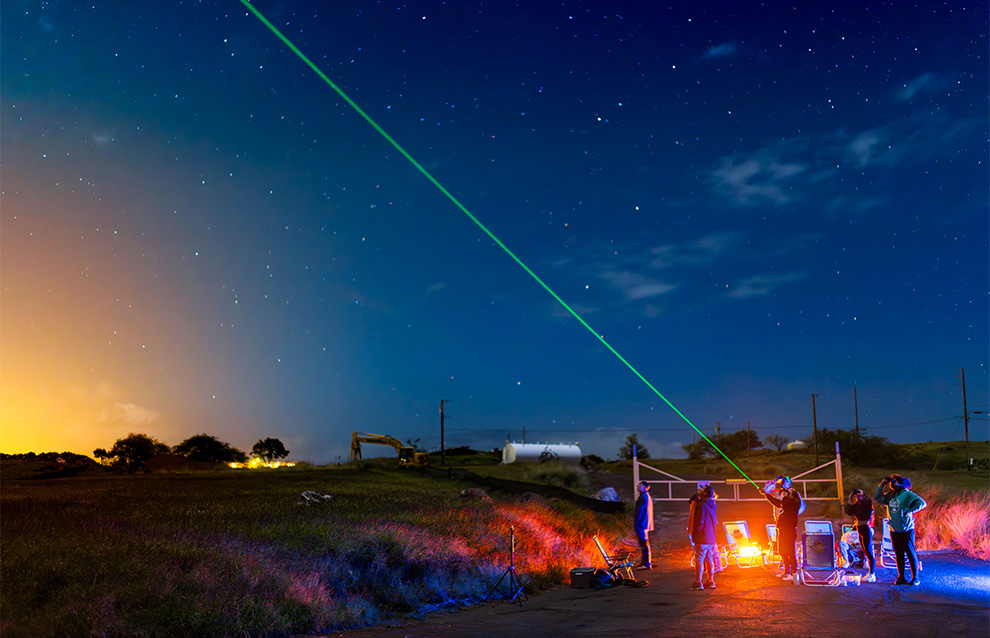 a landscape photo of the night sky with people observing 