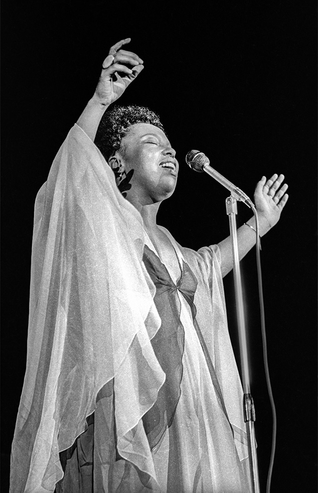 person singing on stage wearing a dress