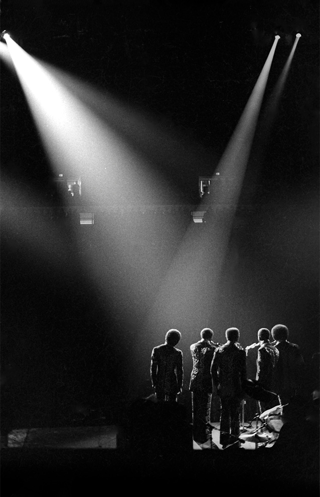 a group of peple on stage performing with two spotlights on them