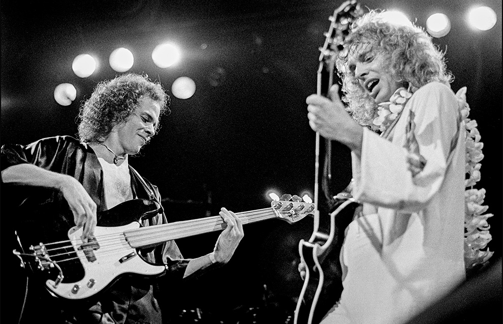 two people playing electric guitars on stage