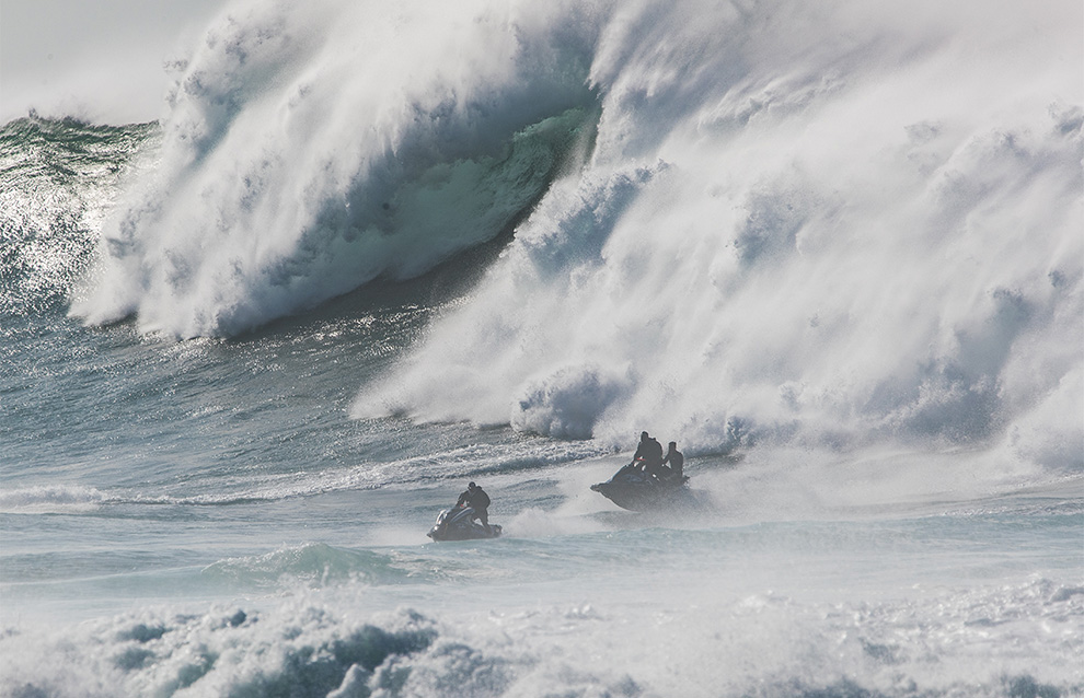 a closeup of waves with two people on jetskis